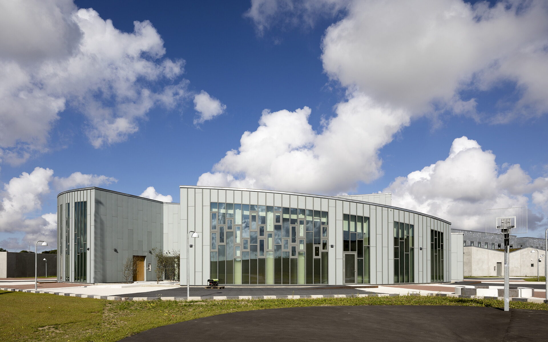 Image of Storstrøm Prison in Denmark. Cloudy day, green grass, built structure in center.