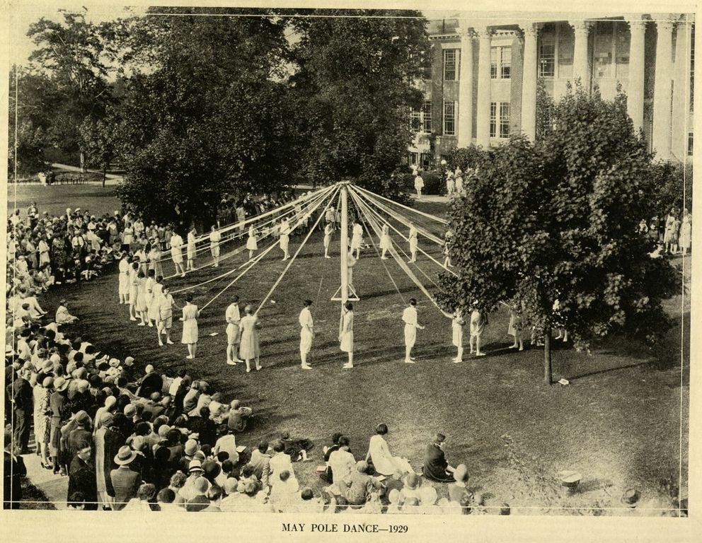 Students dancing around a MayPole. With ribbons, in a circle. 